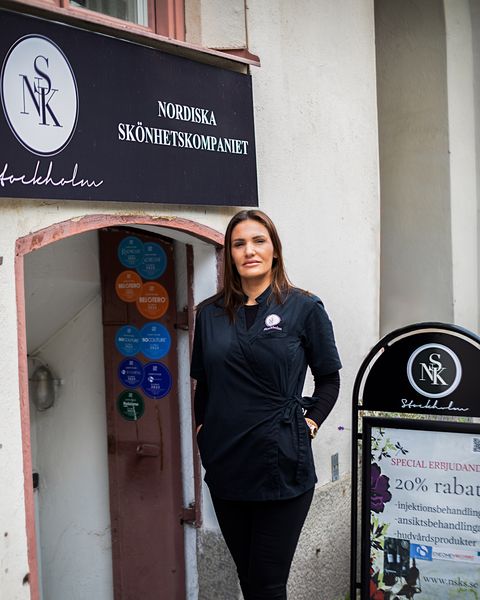 Jelena vid entrén till kliniken, under den svarta skylten